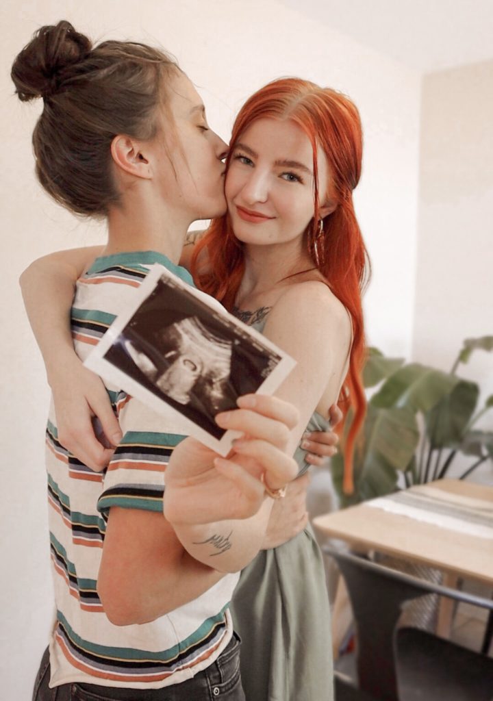 Lesbian Couple kissing holding a baby sonogram