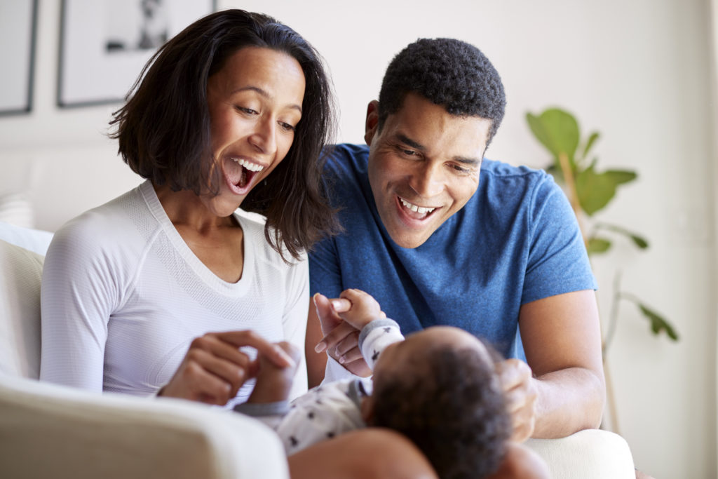 a mom and dad smiling at their baby and playing with him that match