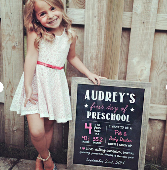 little girl posing with a chalkboard saying "first day of preschool"